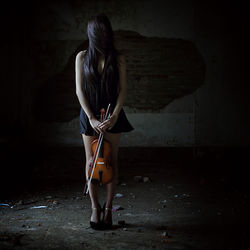 Woman holding violin on street at night