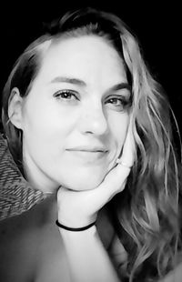 Close-up portrait of smiling young woman against black background
