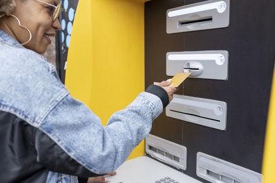 Smiling woman inserting credit card in atm machine