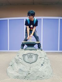 Full length of boy sitting against wall