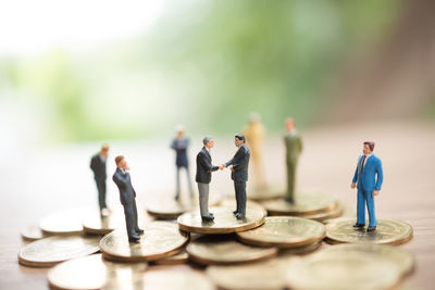 Close-up of figurines with coins on wooden table