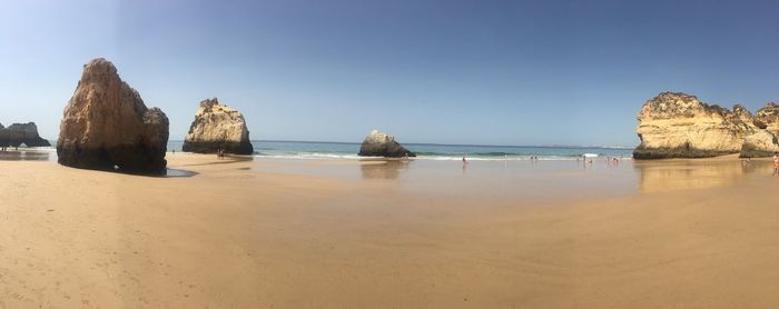 Panoramic view of rocks on beach against clear sky