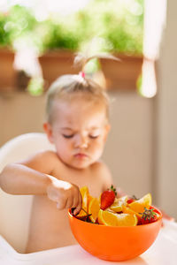 Cute girl sitting in bowl on table