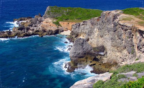 Rock formations by sea against blue sky