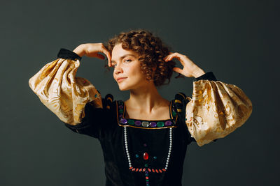 Portrait of young woman standing against black background