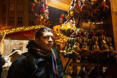 Portrait of man looking at illuminated market at night