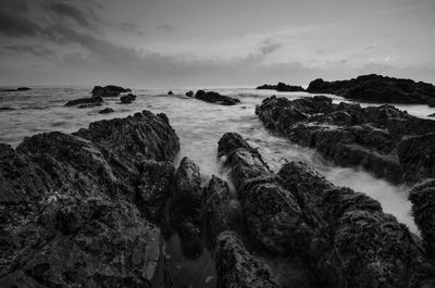 Scenic view of rocks on beach against sky