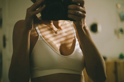 Midsection of woman in the bra in the mirror, standing at home