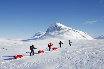 People on snowcapped mountain against sky