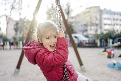 Portrait of girl sitting on swing at park