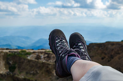 Low section of man relaxing against sky