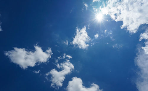 Low angle view of sunlight streaming through clouds