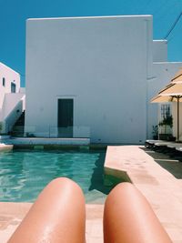 Low section of person relaxing in swimming pool against building