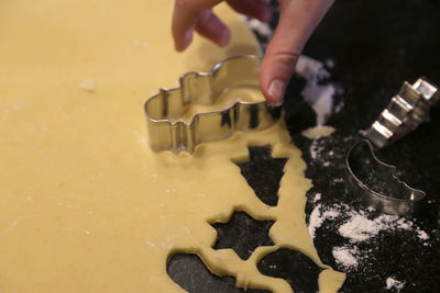 Cropped hand of woman making cookies in kitchen