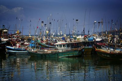 Boats moored at harbor against sky