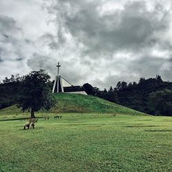 Scenic view of grassy field against cloudy sky