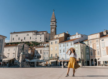 Stylish young woman standing in tartini square in idyllic town of piran, slovenia
