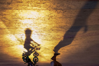 Shadow of people riding bicycle on street