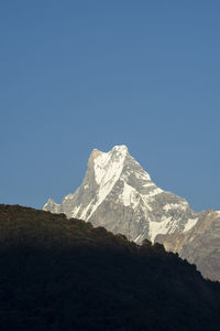 Scenic view of snowcapped mountains against clear blue sky