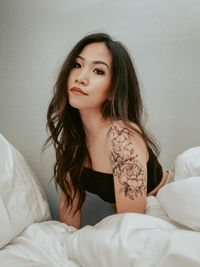 Girl with tattoos sitting on her bed 