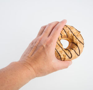 Close-up of hand holding bread against white background