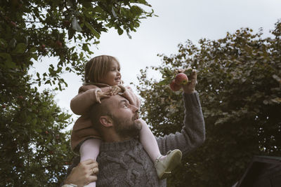 Father carrying his little daughter on shoulders