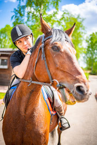 Young woman riding horse on sunny day