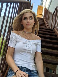 Low angle view of teenage girl sitting by railing on staircase