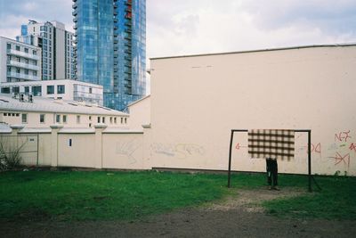 Information sign on field by buildings against sky