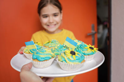 Ukrainian girl for whom neighbors brought cupcakes with cream in yellow and blue colors for brunch