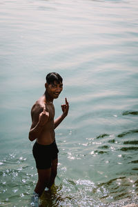 Full length of shirtless man standing in sea