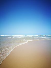 Scenic view of beach against clear blue sky