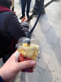 Midsection of man holding ice cream on footpath