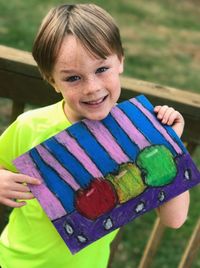 Close-up portrait of happy boy holding drawing