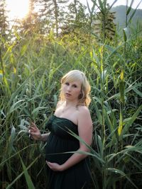 Portrait of pregnant woman standing amidst plants