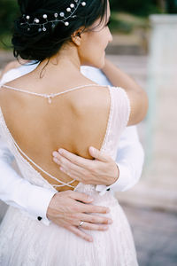 Rear view of woman with arms raised standing outdoors