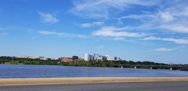 City at waterfront against cloudy sky