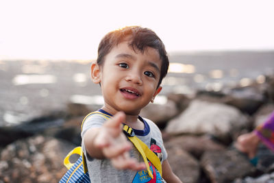 Portrait of boy standing on beach against sky