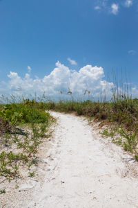 Road amidst field against sky