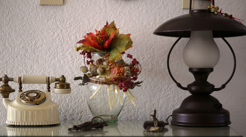 Close-up of flower vase on table against wall at home