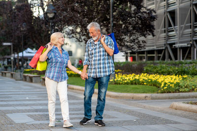 Full length of senior couple with shopping bags walking on street