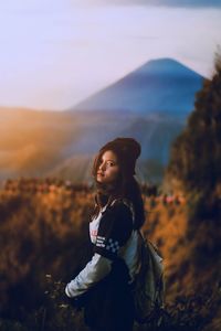 Young woman standing on land against sky