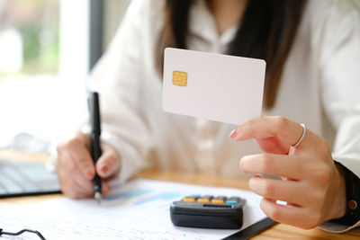 Midsection of woman using mobile phone at table