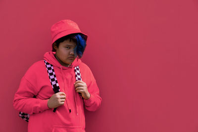 Back to school. a teenage girl with blue hair in pink hoodie, panama hat with backpack. high school