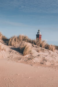 Lighthouse on beach against sky