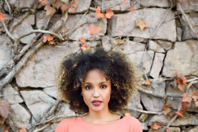 Close-up portrait of young woman against stone wall