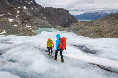 Rear view of men with umbrella on snowcapped mountain