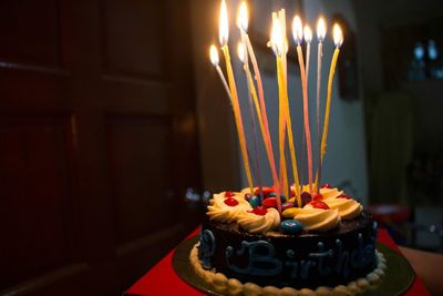 Lit birthday candles on cake at stool