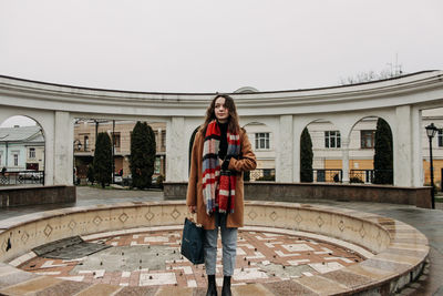 Portrait of smiling young woman standing against building