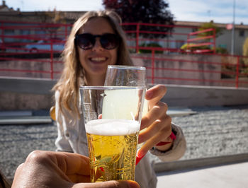 Cropped hand of friend toasting drinks with smiling woman